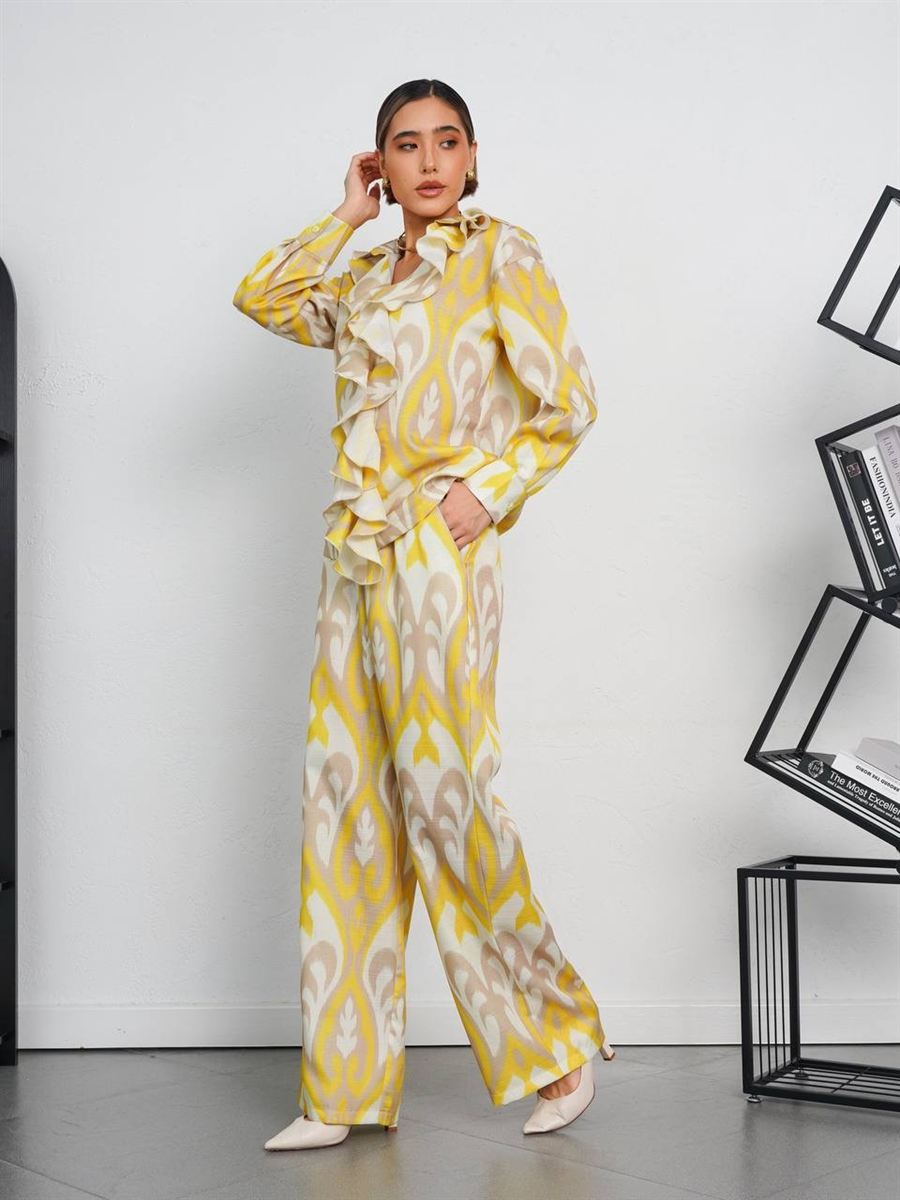 Светлый костюм с жёлтым узором, блузой с воланами и широкими брюками